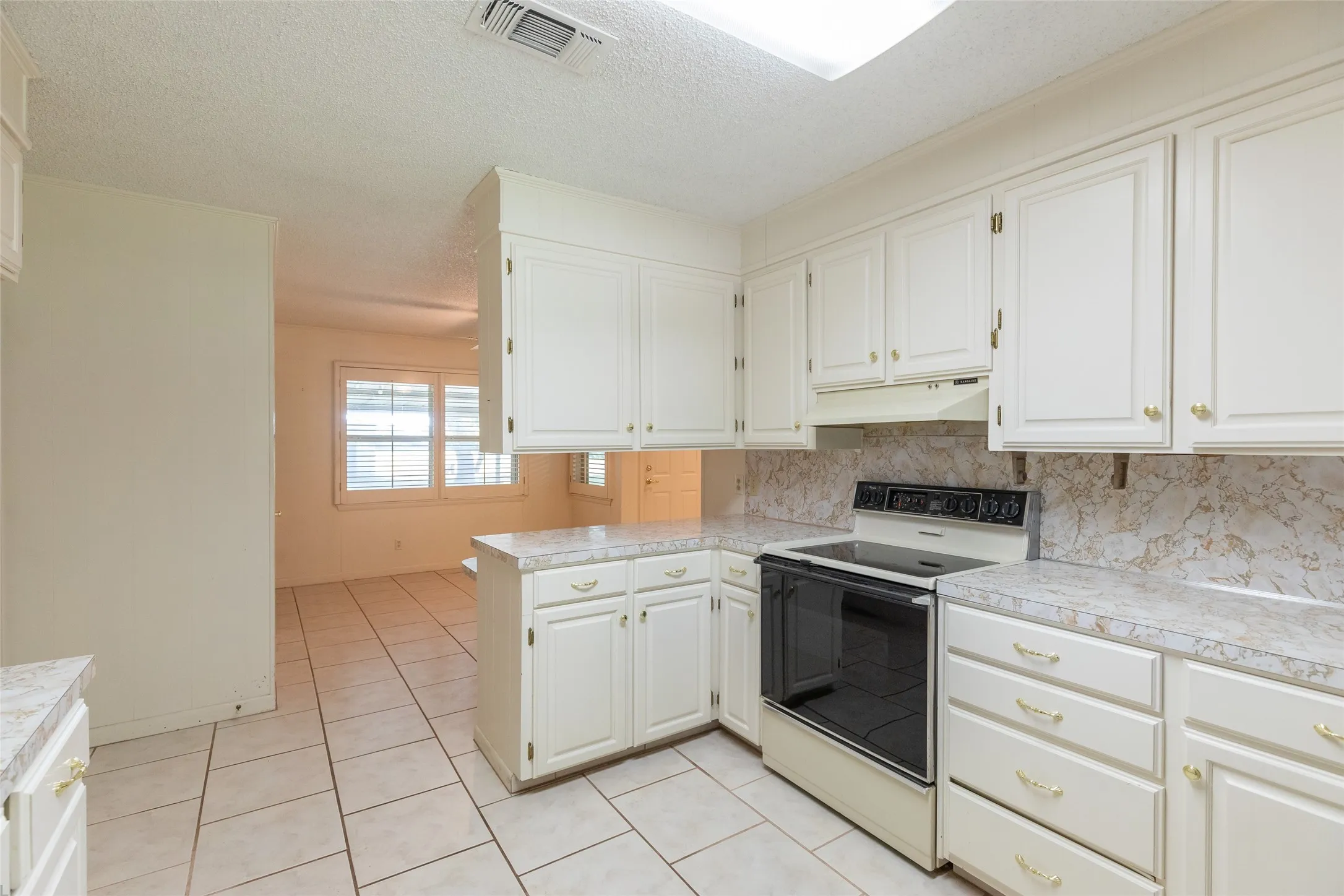 Kitchen featuring white cabinetry, a built-in range, and a skylight