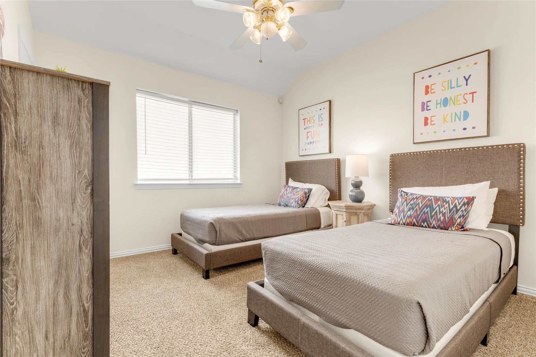Carpeted flooring, vaulted ceiling, ceiling fan, window with blinds, and light-toned walls