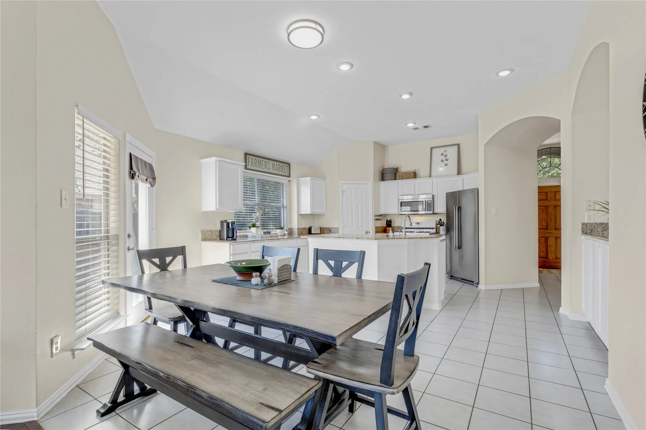 Kitchen with white cabinetry, stainless steel appliances, and light-toned tile flooring