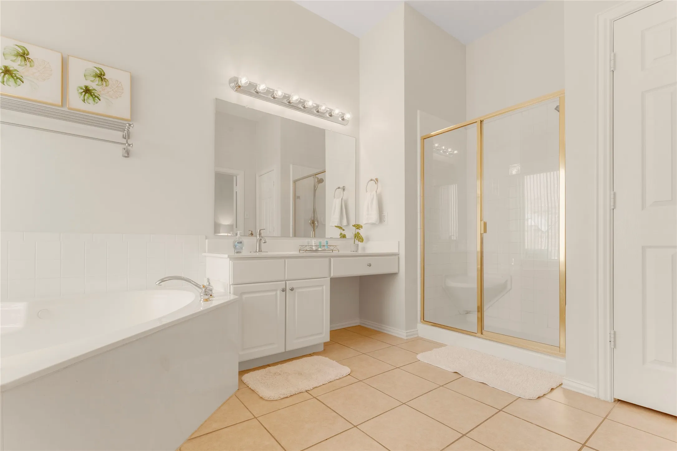 Spacious bathroom featuring a built-in tub, dual vanity with white cabinetry, separate shower with framed glass enclosure, and large format floor tile