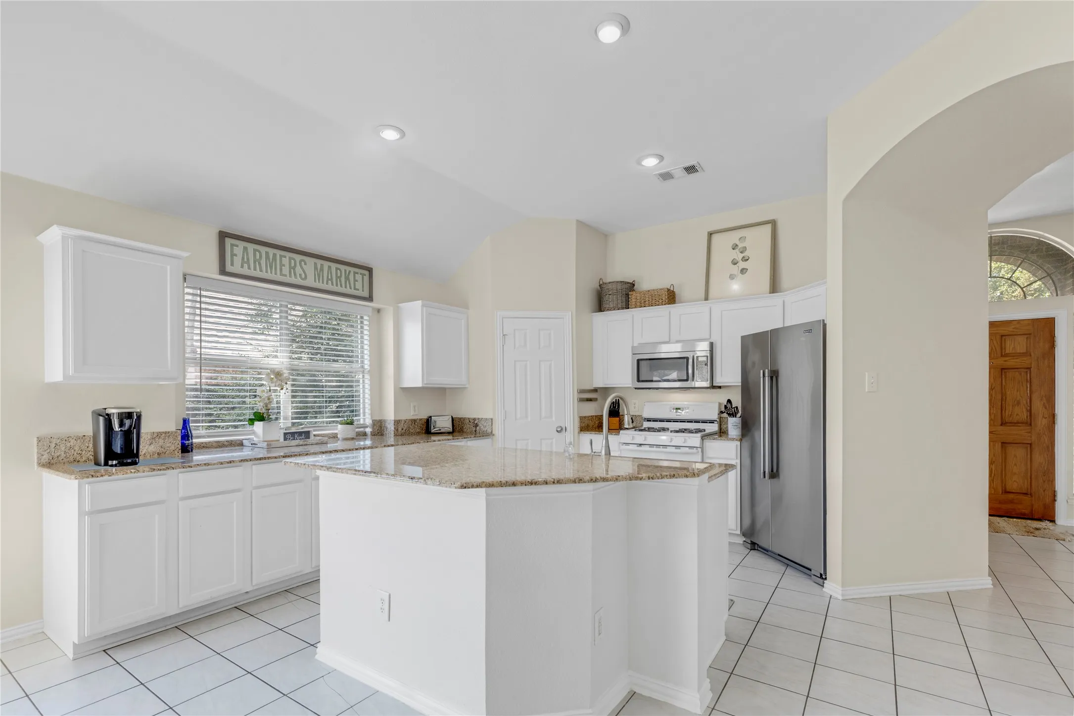 Kitchen featuring white cabinetry, granite countertops, stainless steel appliances, a center island, and tiled flooring
