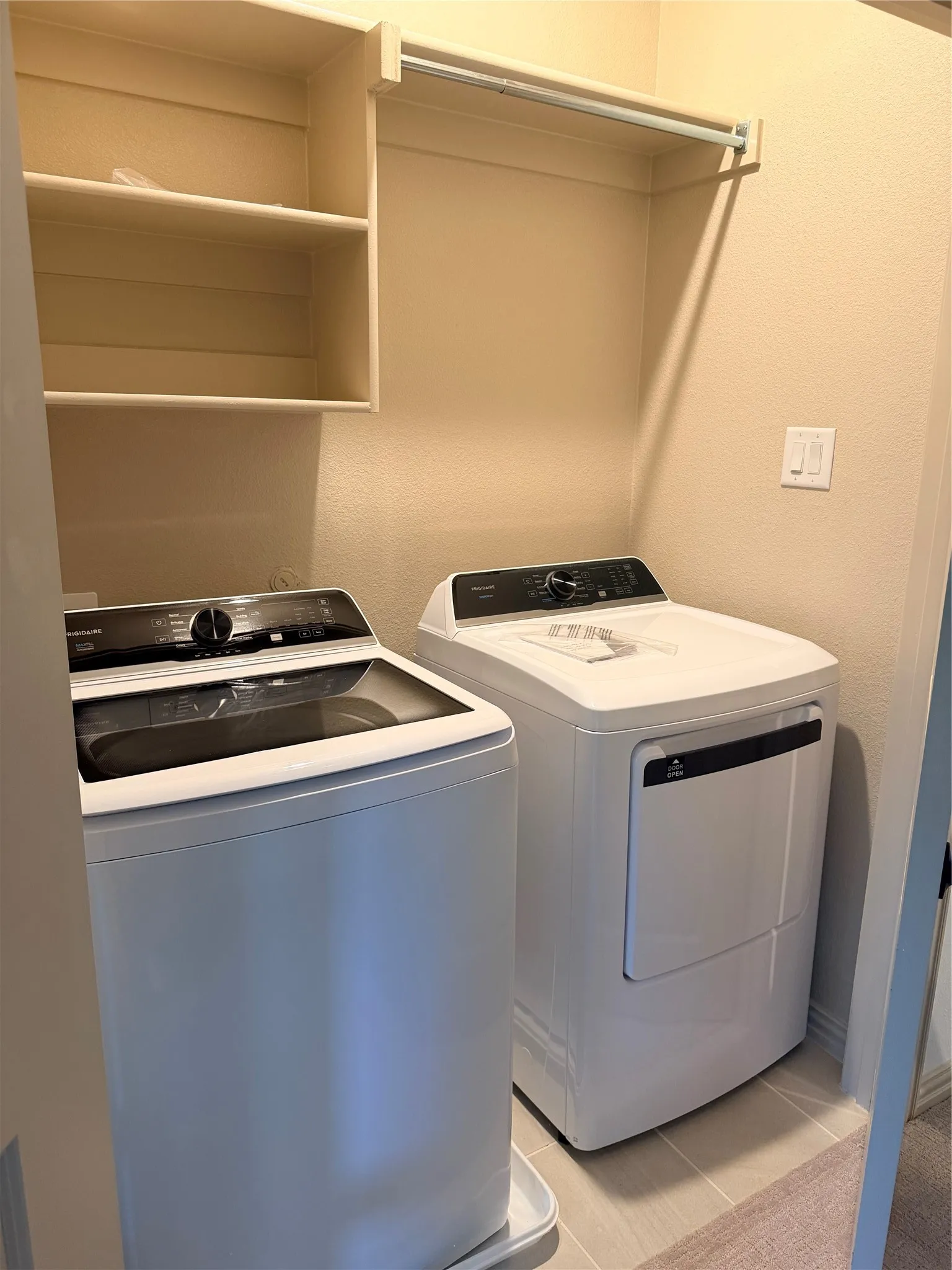 Laundry area featuring built-in shelving, a clothes hanging rod, and tile flooring