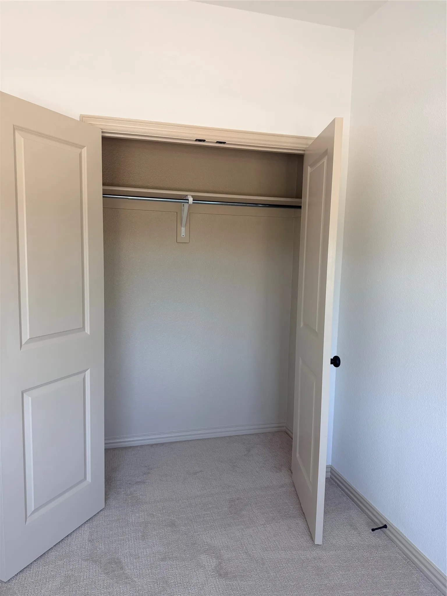 Recessed closet featuring bi-fold panel doors and a chrome hanging rod