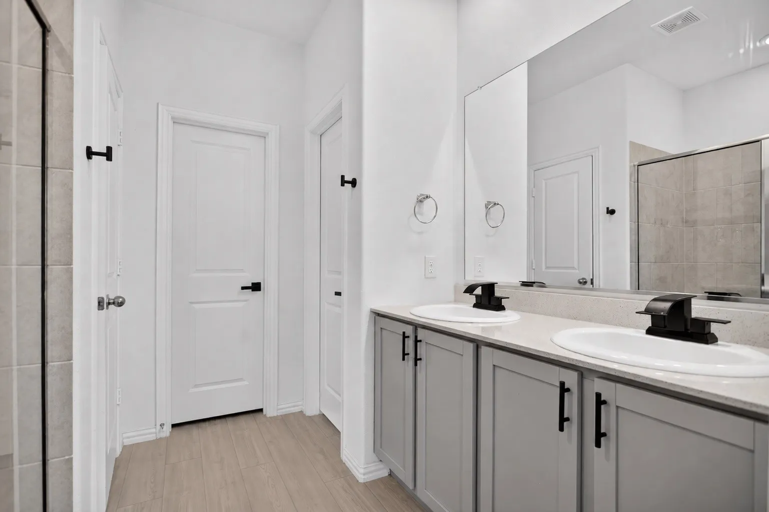 Dual vanity with undermount sinks, light gray cabinetry, and black hardware