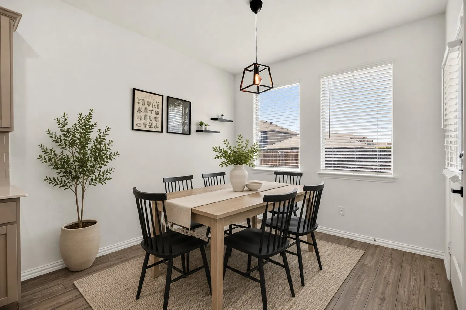 Recessed dining area featuring wood-finish flooring, two large windows, and a contemporary geometric pendant light