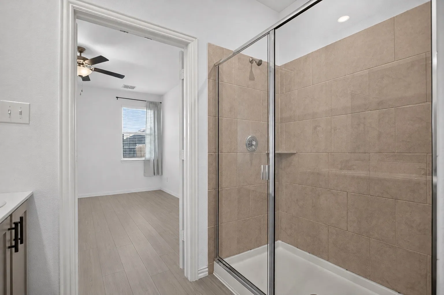 Glass-enclosed shower with ceramic tile surround and built-in shower niche