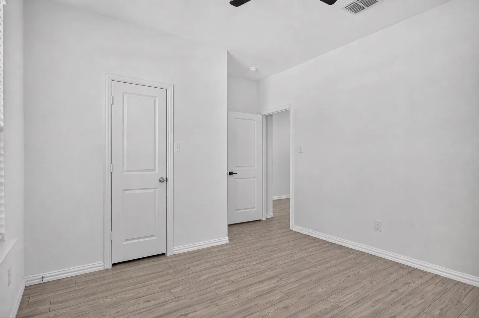 Wood-finish flooring with white baseboards and painted walls