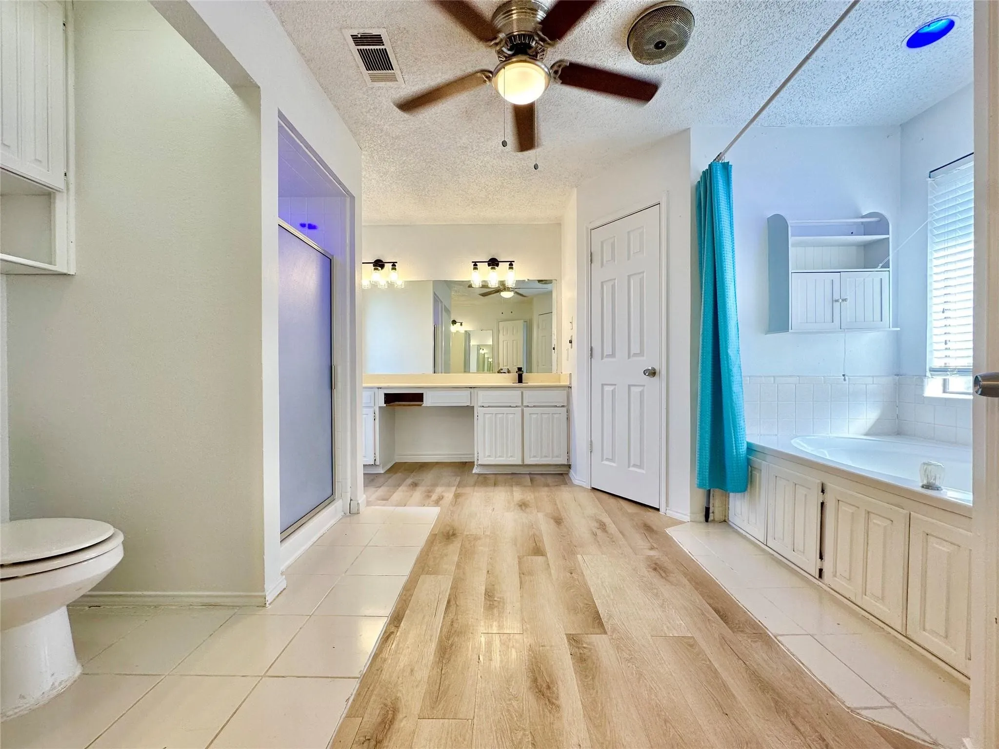 Wood-finish flooring leading to a built-in vanity with double sinks