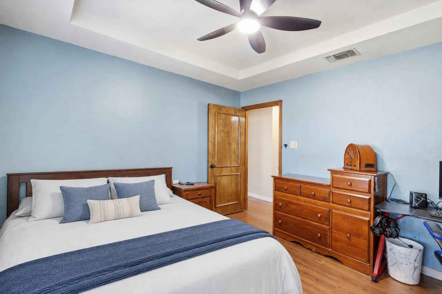 Wood-finish flooring, tray ceiling, ceiling fan, and wood-paneled door