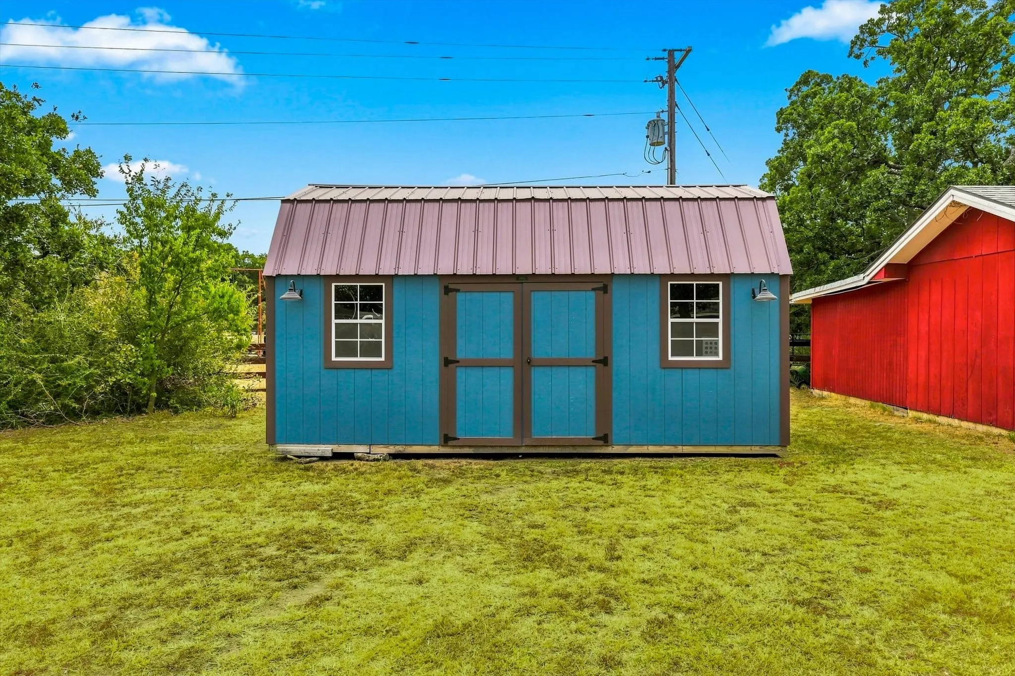 Freestanding shed with a metal roof, double doors, and two windows