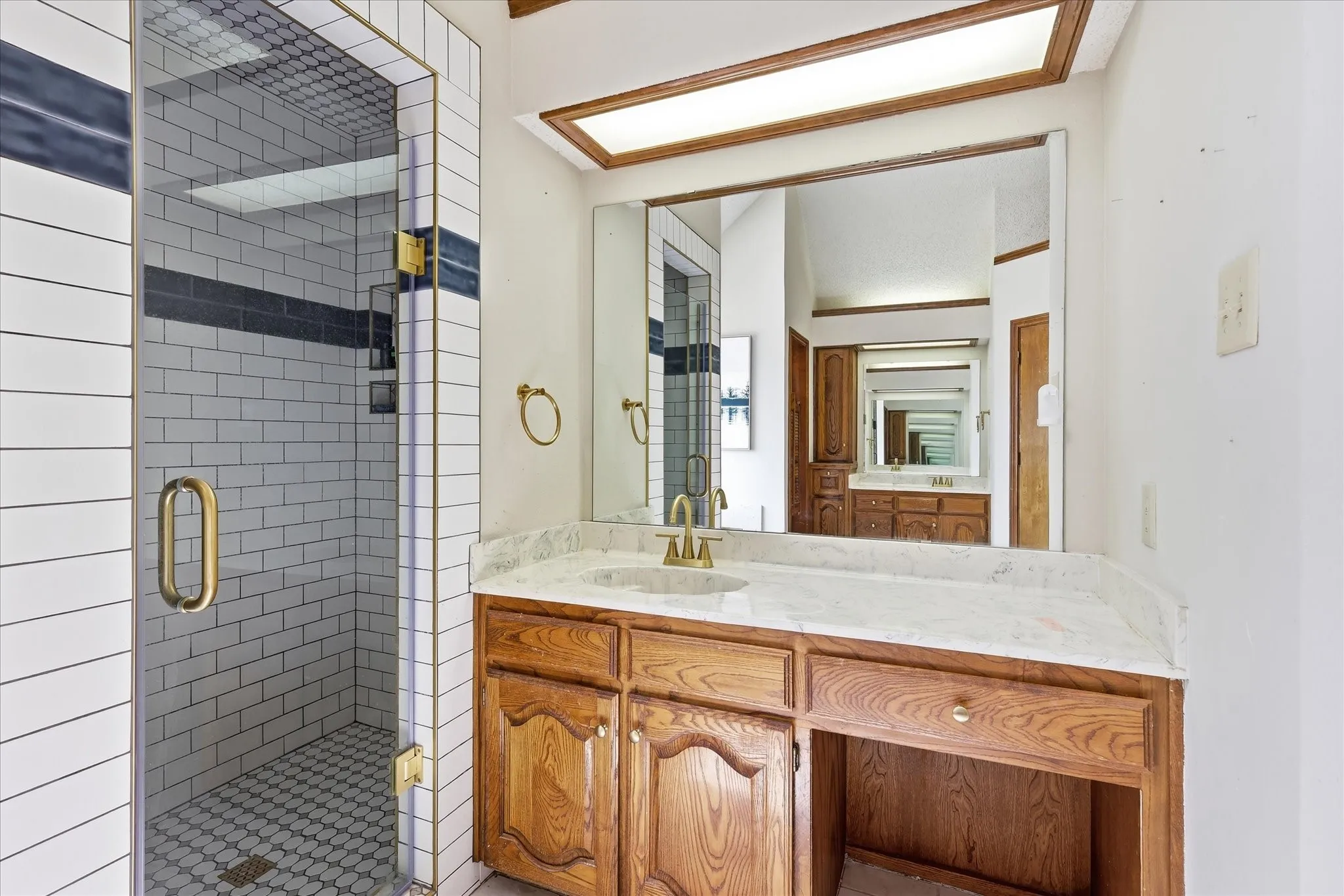 Custom tiled shower with clear glass enclosure and brass-finish hardware