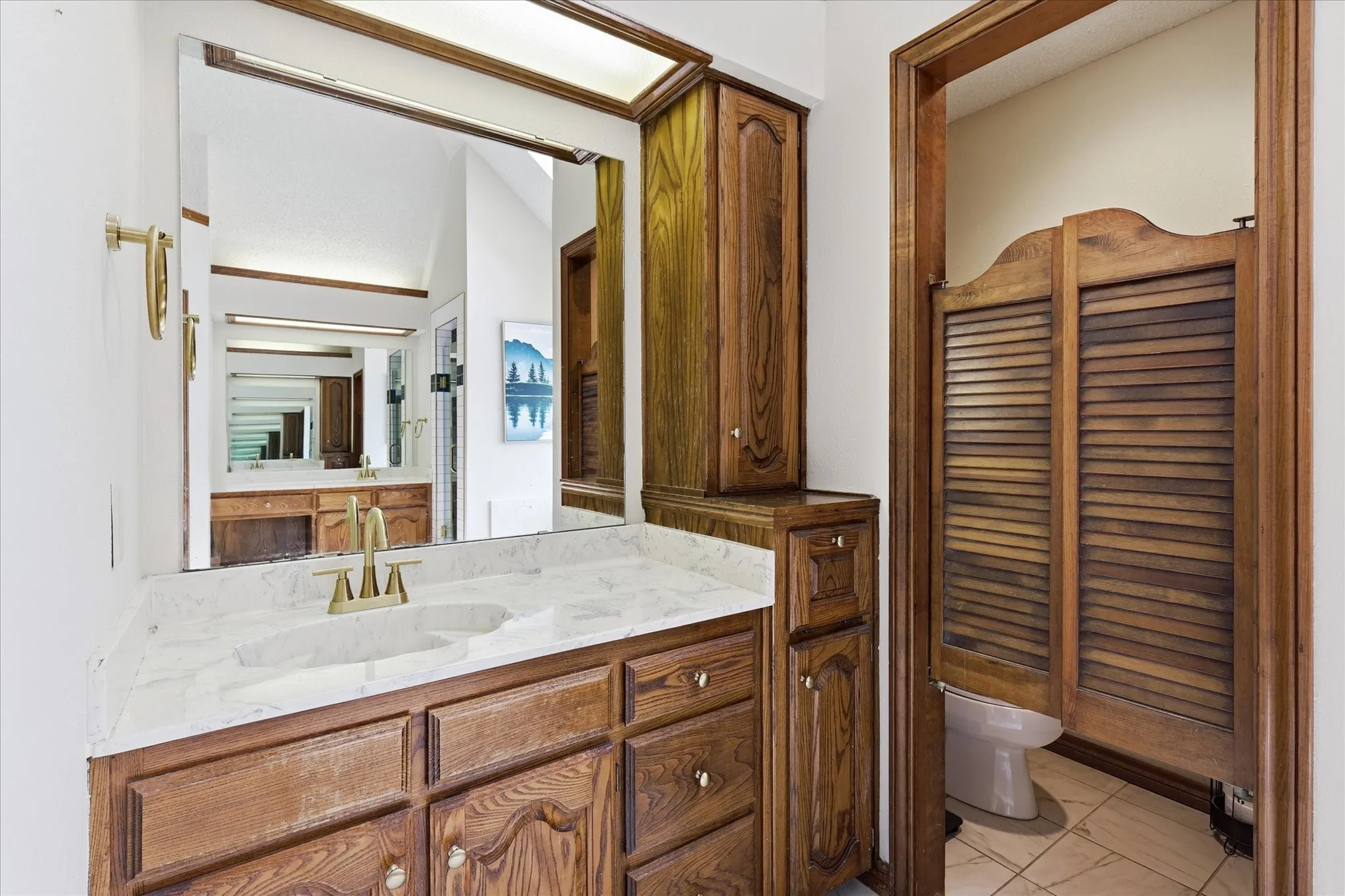 Wood-finish vanity with a single basin, gold-tone faucet, and white countertop