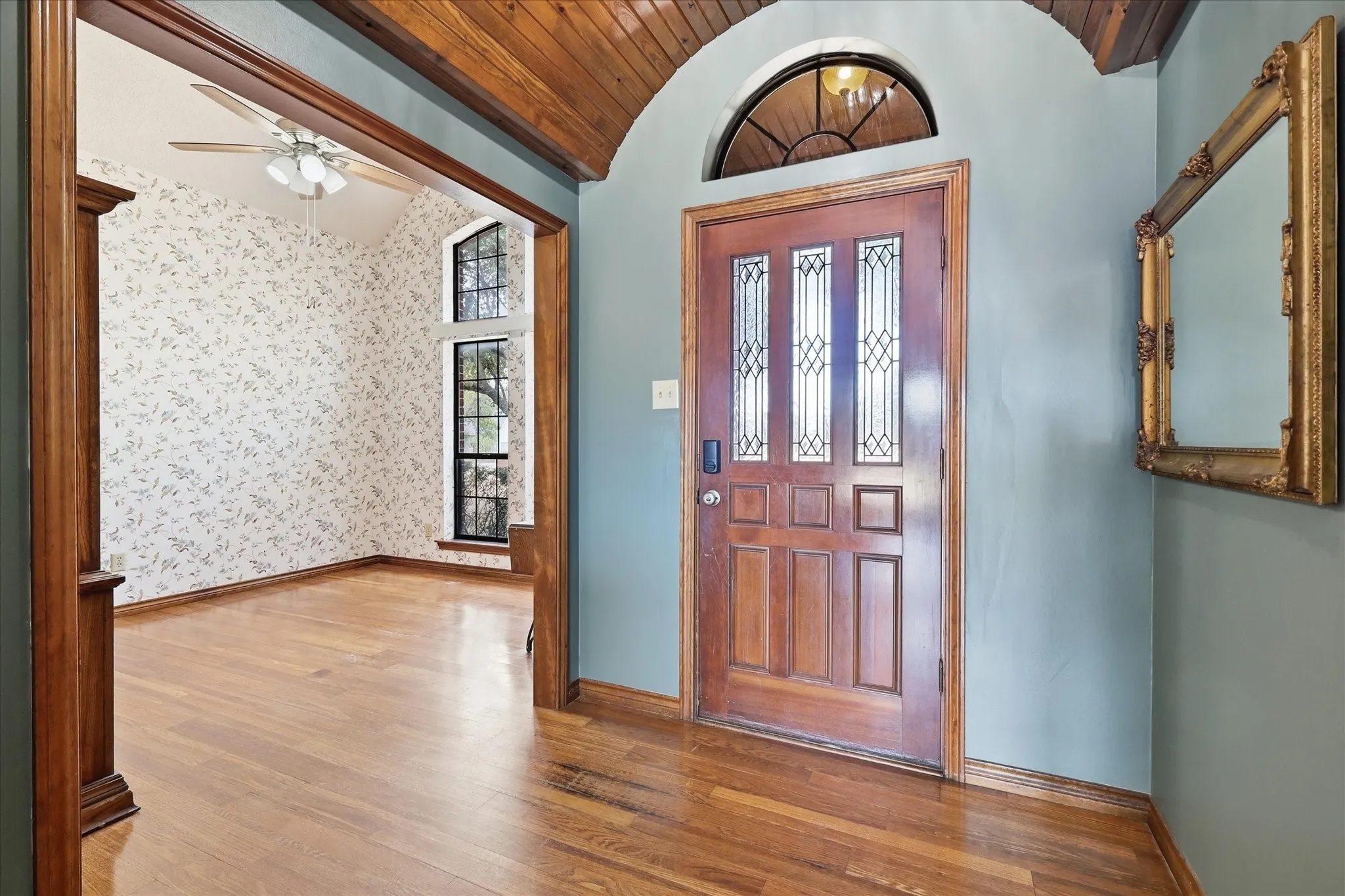 Wood-paneled entryway with an arched ceiling and wood-finish flooring
