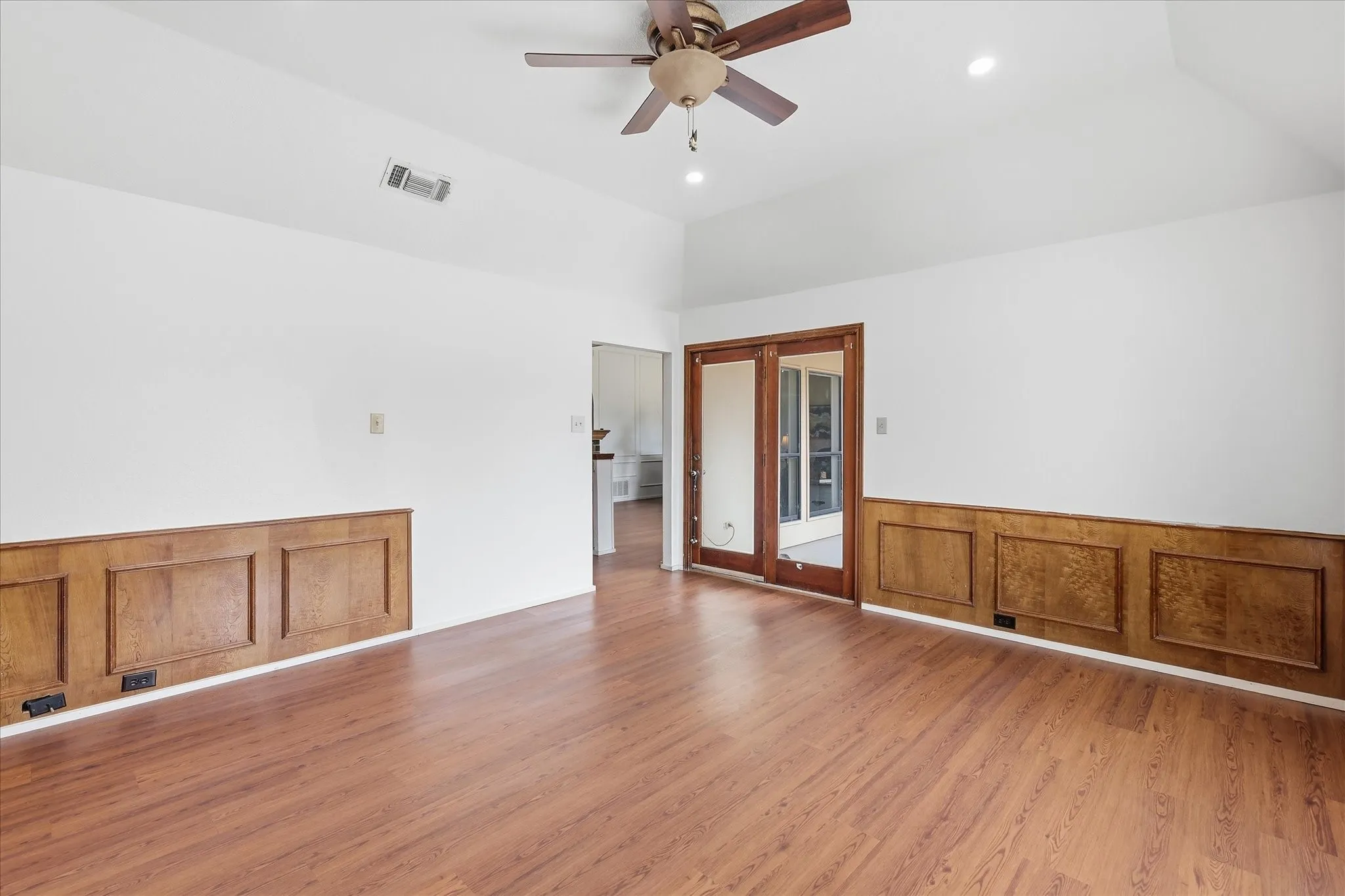 Vaulted ceiling with recessed lighting, wood-finish flooring, wood paneling, and double glass-paned doors