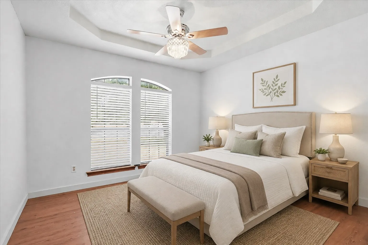 Tray ceiling with ceiling fan and light fixture, arch-top windows with blinds, wood-finish flooring