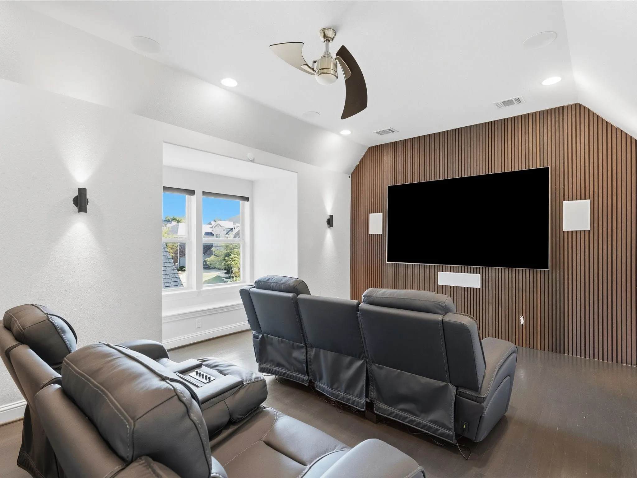Hardwood flooring, slatted wood accent wall, recessed lighting, ceiling fan, and built-in speakers