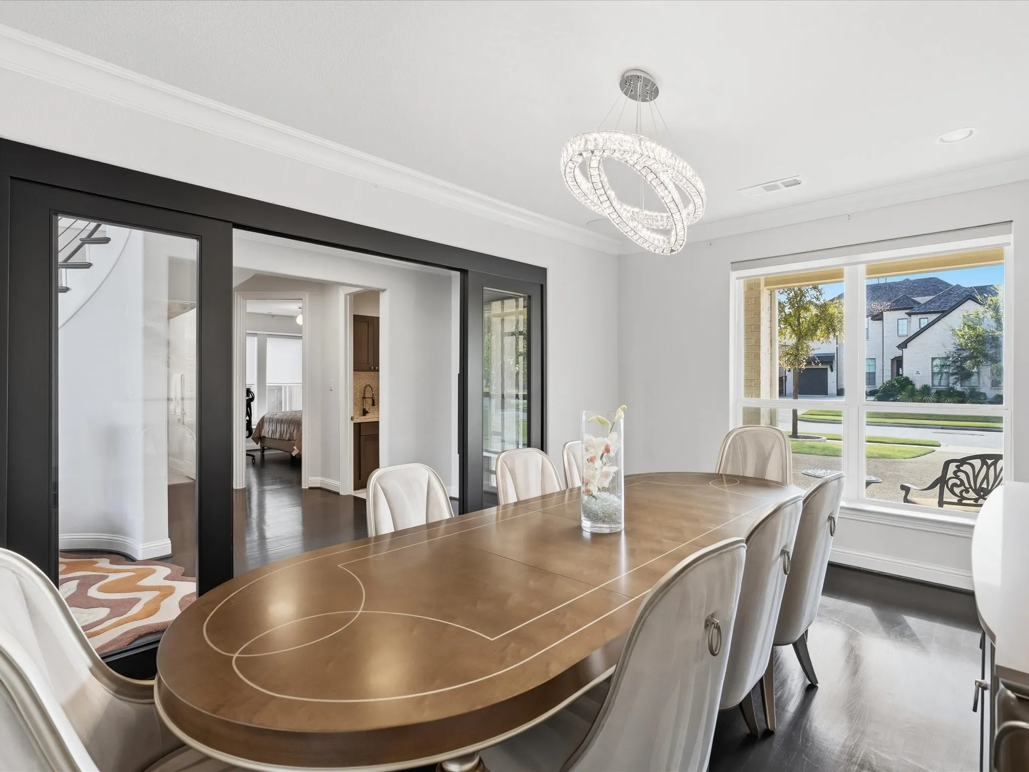 Recessed lighting, crown molding, a modern crystal chandelier, dark wood-finish flooring, and expansive windows