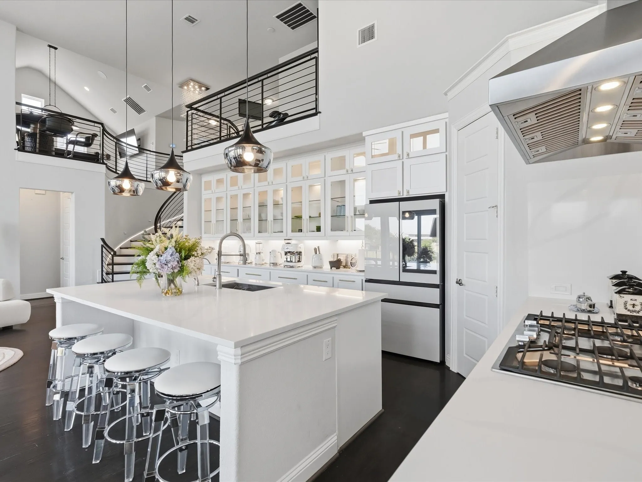 Kitchen featuring a white countertop island, pendant lighting, white cabinetry, integrated refrigerator, and gas cooktop