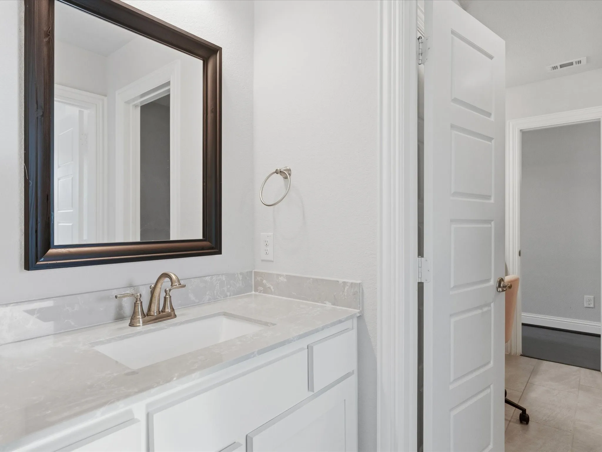 White vanity with an integrated sink, light-toned countertop, and framed mirror
