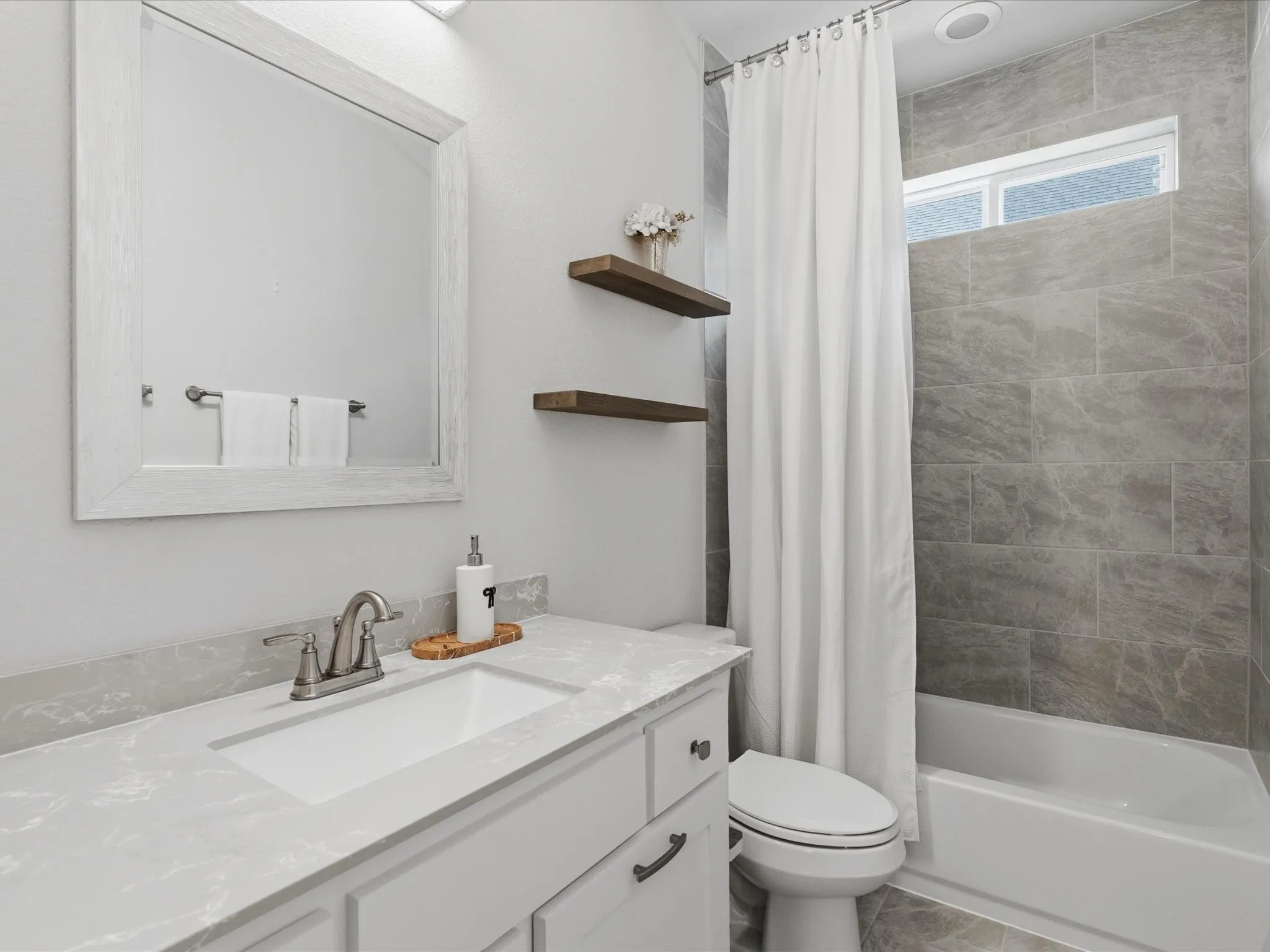 Vanity with white shaker-style cabinetry, undermount sink, and light-toned countertop