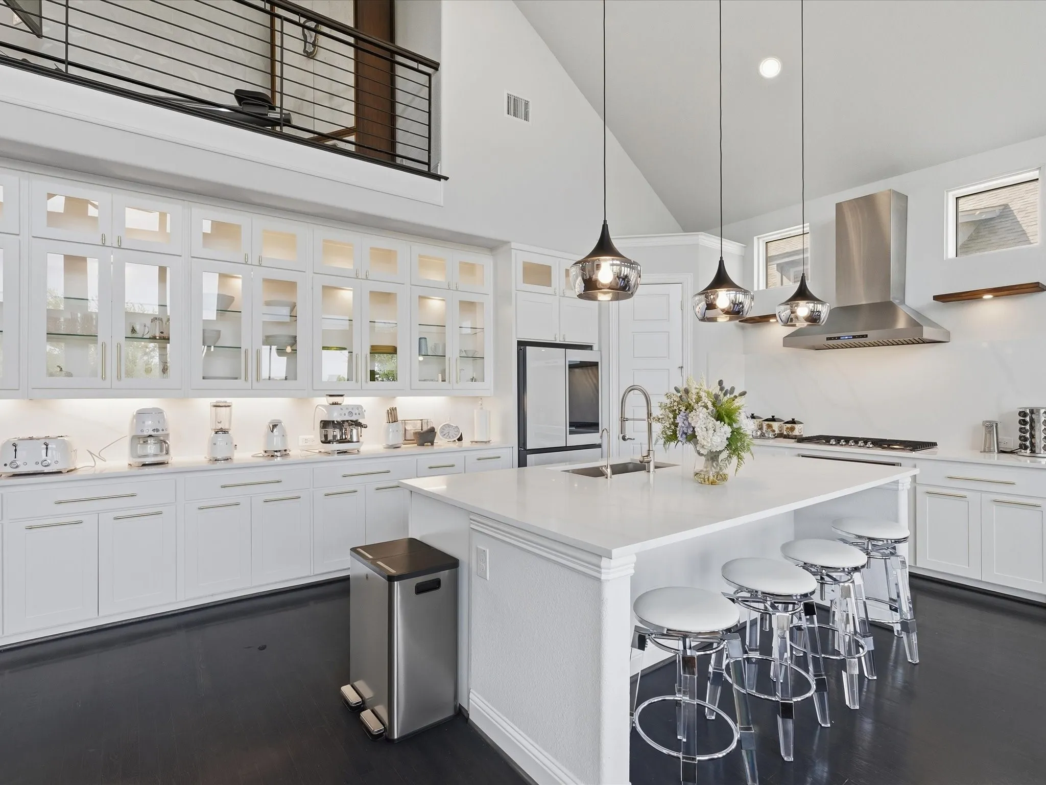 Gourmet kitchen with an expansive island, white cabinetry, integrated stainless steel appliances, and dark wood-finish flooring