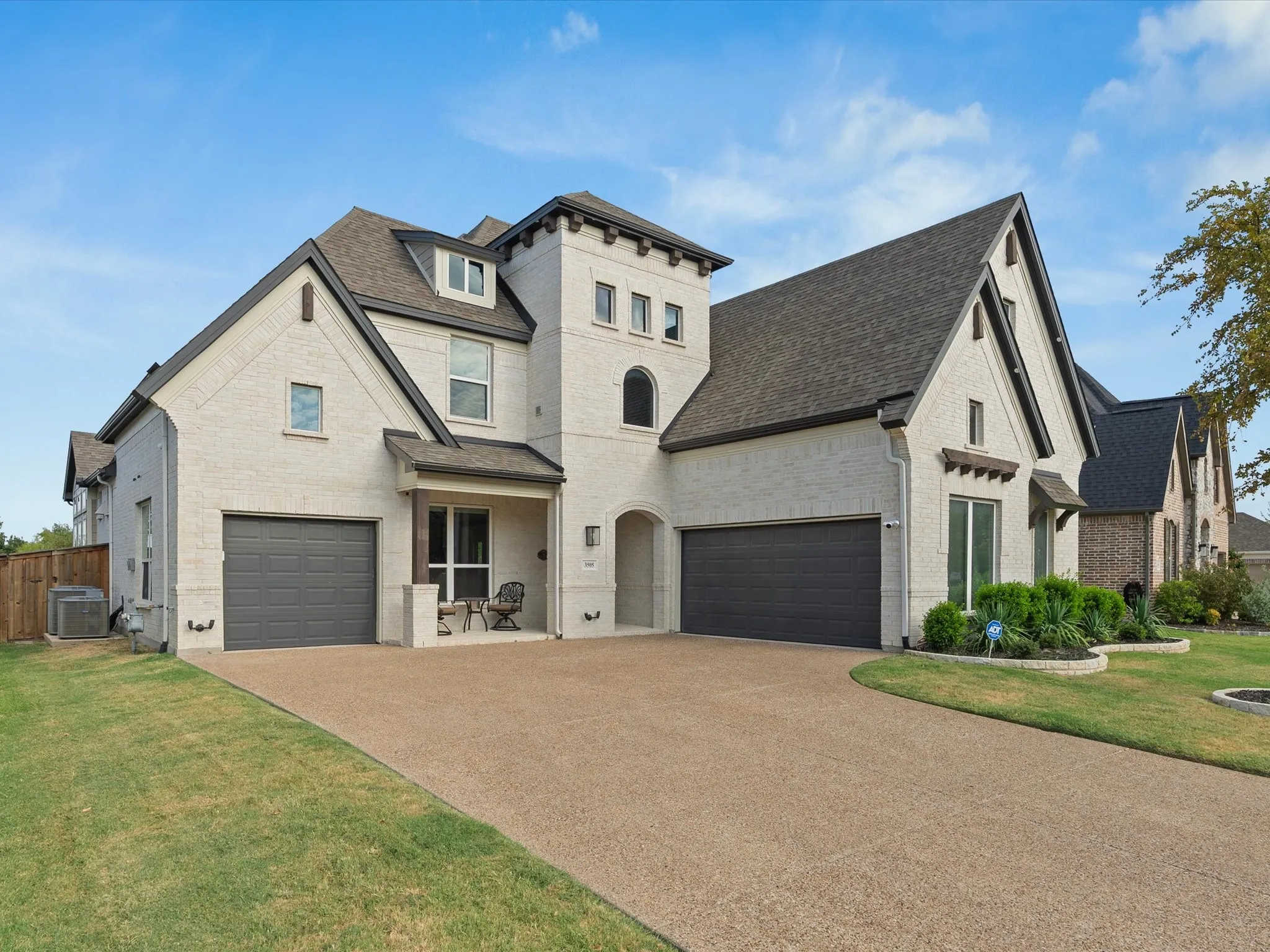 Striking two-story residence featuring a cream and stone exterior with multiple peaked rooflines and architectural detail