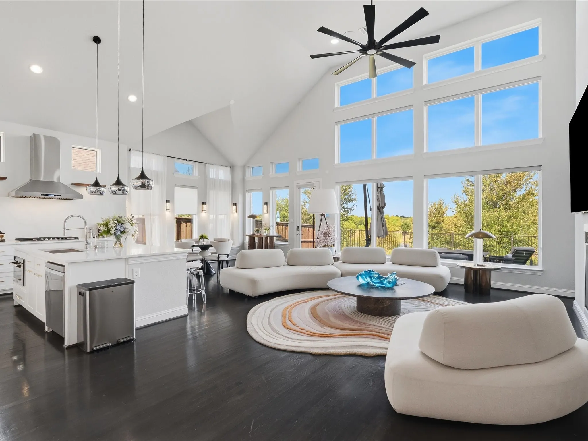 Vaulted ceilings with an exposed beam, a full wall of windows, a kitchen island with seating, dark wood-finish flooring, and pendant lighting