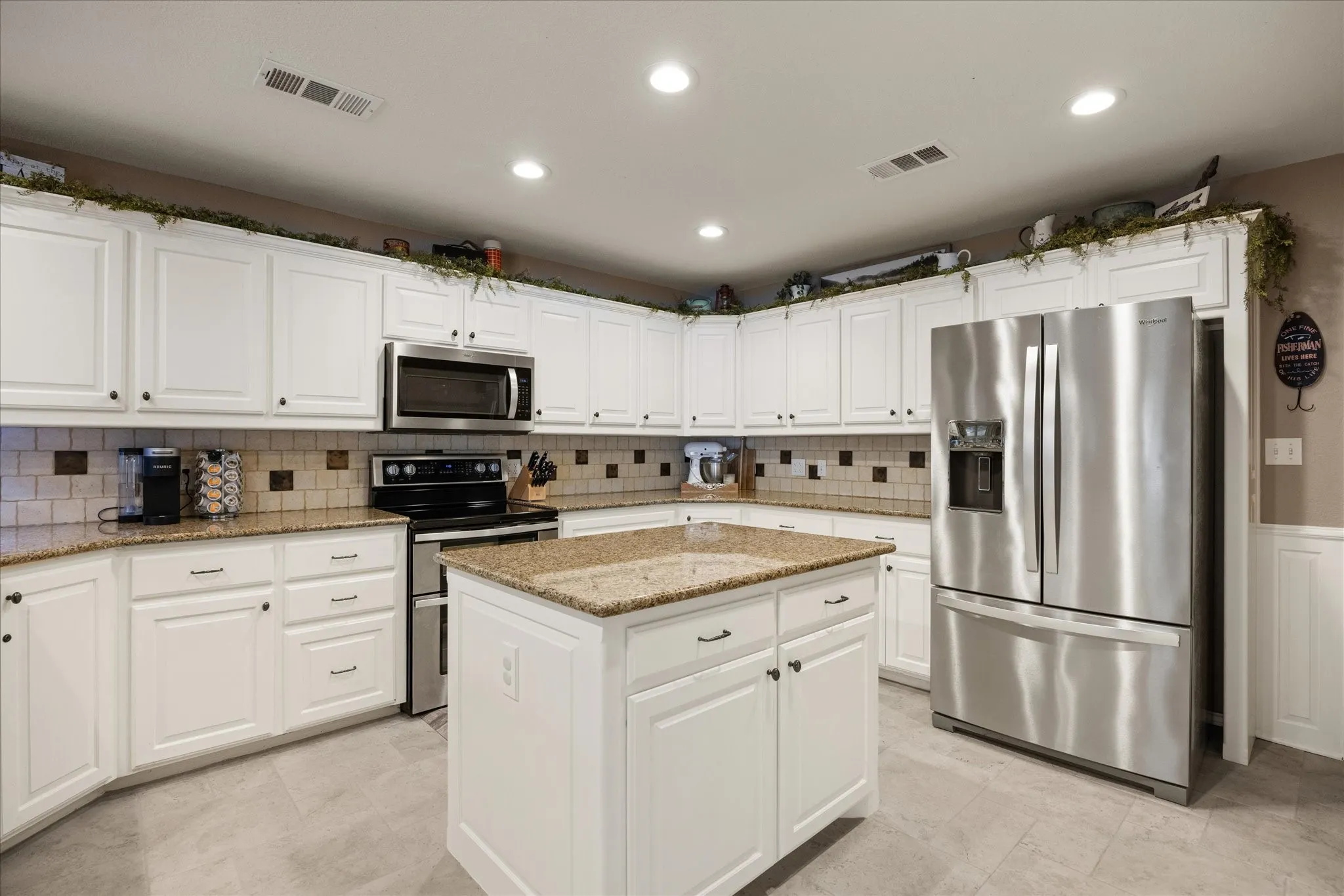 Kitchen featuring white cabinetry, a central island, stainless steel appliances, granite countertops, and recessed lighting