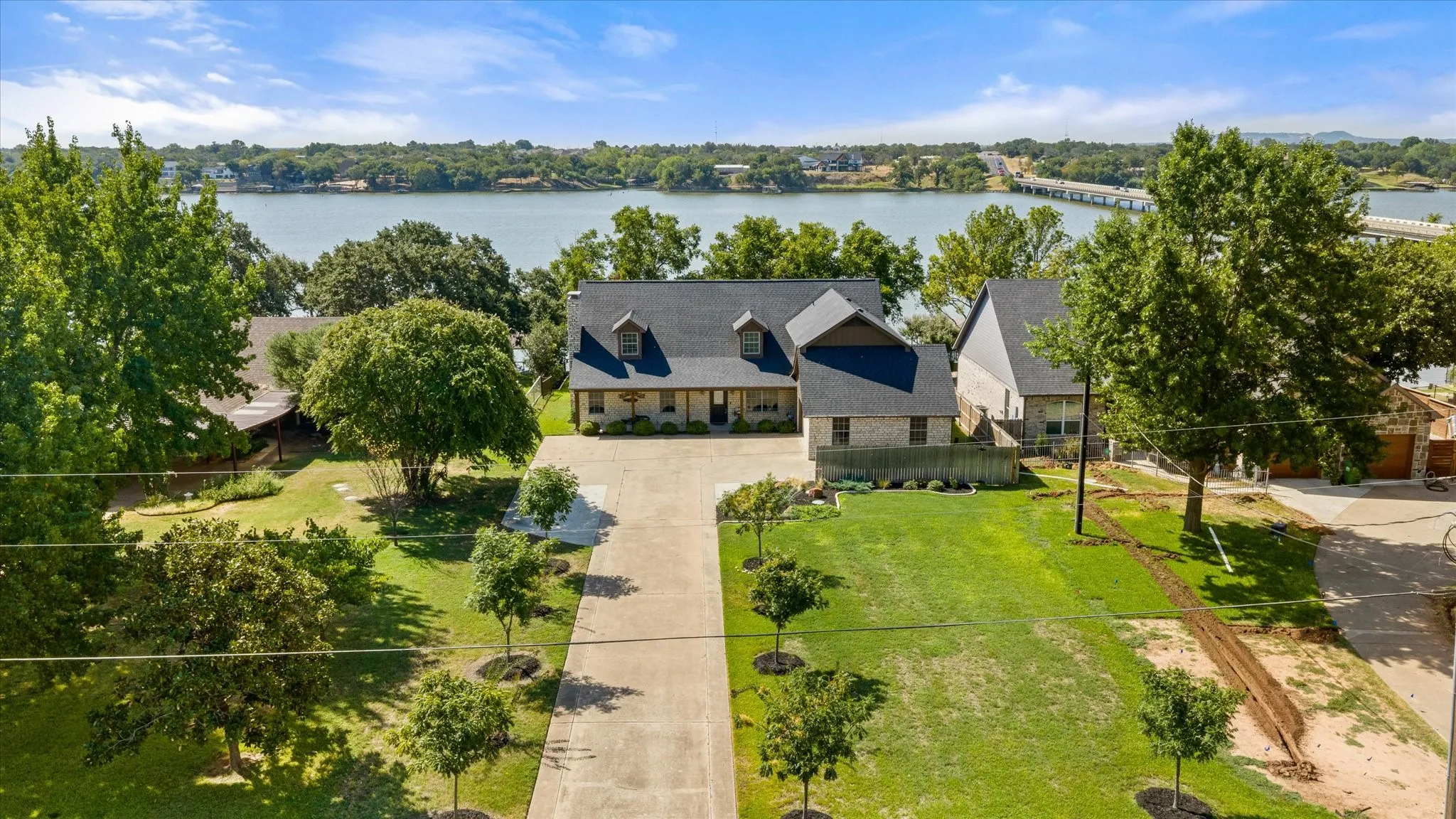 Elegant residence situated on expansive grounds featuring mature landscaping, manicured lawn, and waterfront setting
