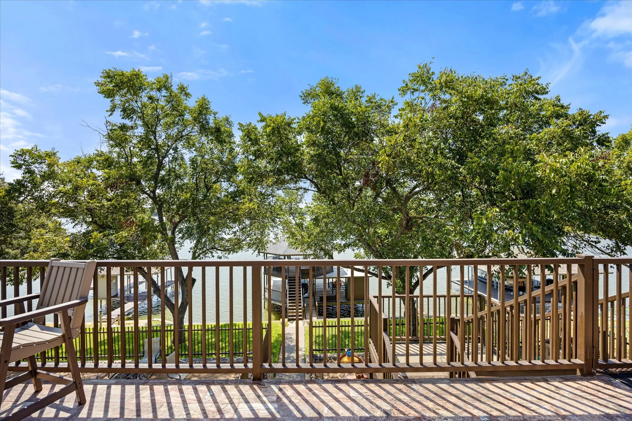 Spacious composite deck with horizontal wood-finish railings and balusters, anchored by mature shade trees and expansive lawn beyond