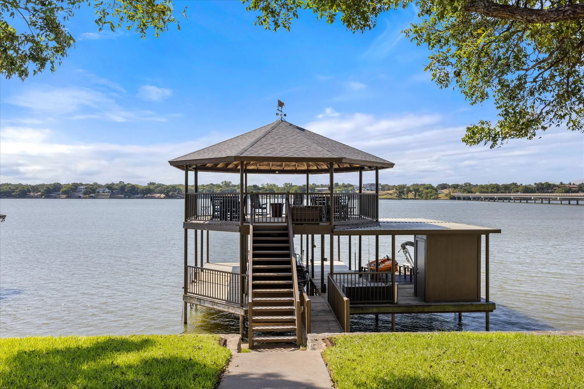Waterfront gazebo with multi-level deck featuring composite decking, wood railings, and a peaked roof structure