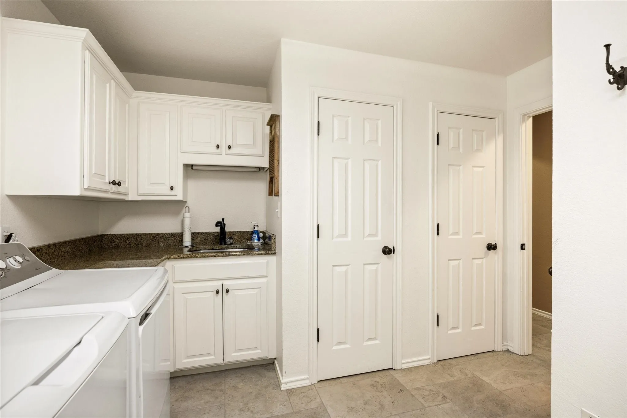 Laundry area with white cabinetry, a sink with dark faucet, and a stone-finish countertop