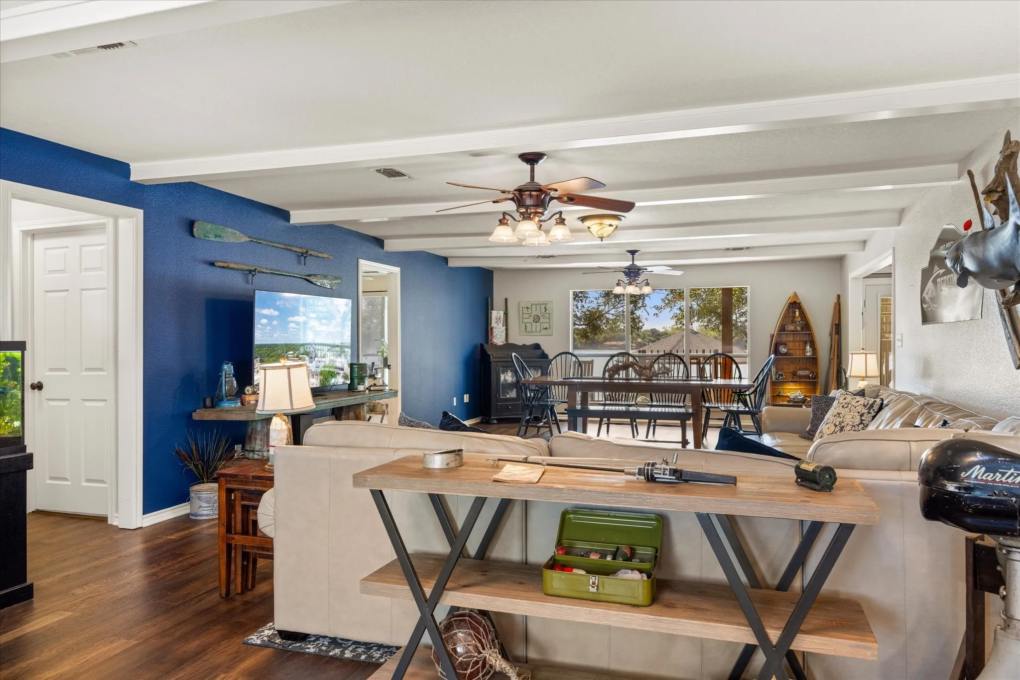 Open-concept living space showcasing hardwood flooring, bold blue accent walls, and coffered white ceiling with integrated lighting