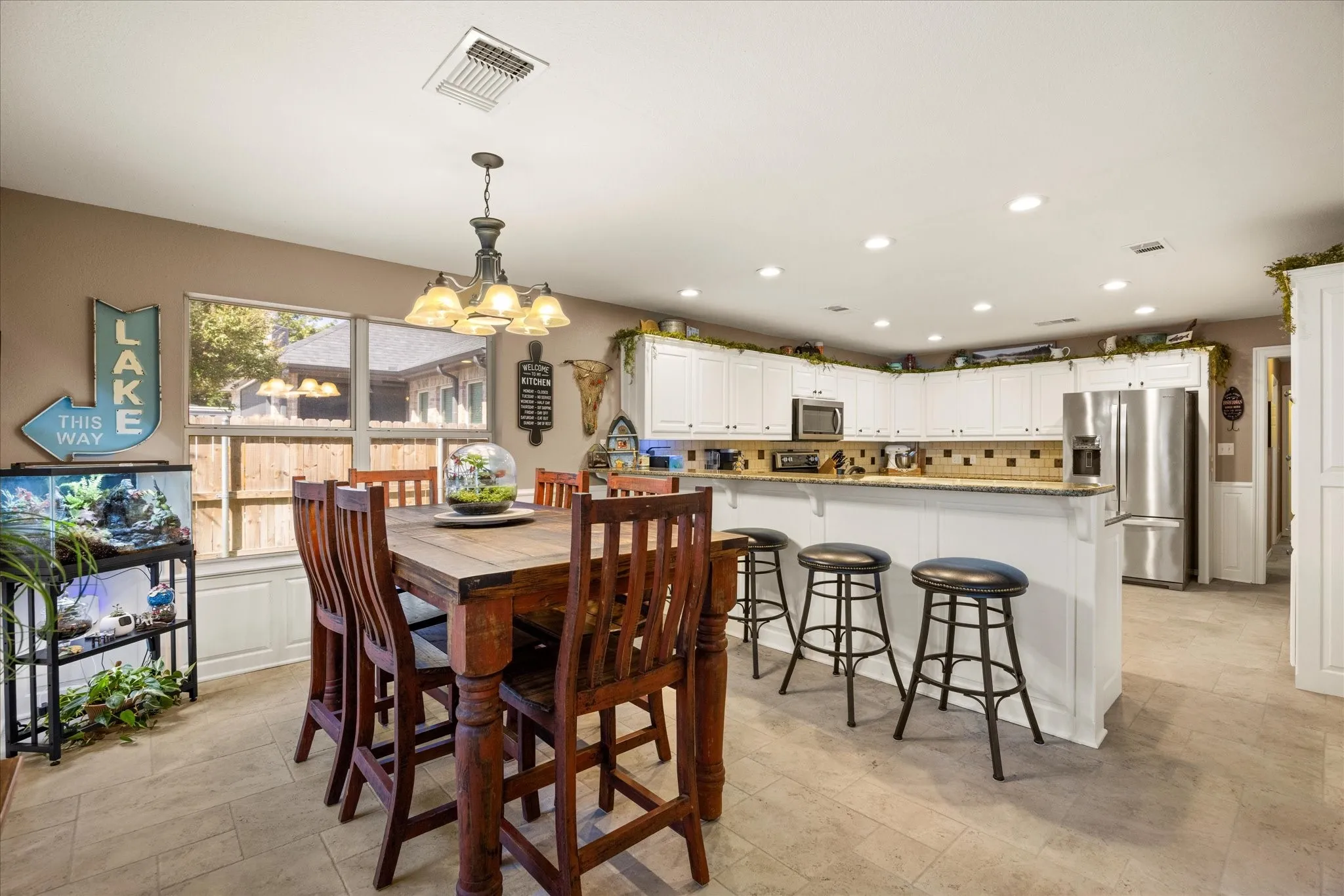 Open-concept kitchen and dining area featuring white cabinetry, stone countertops, a breakfast bar, recessed lighting, and tile flooring