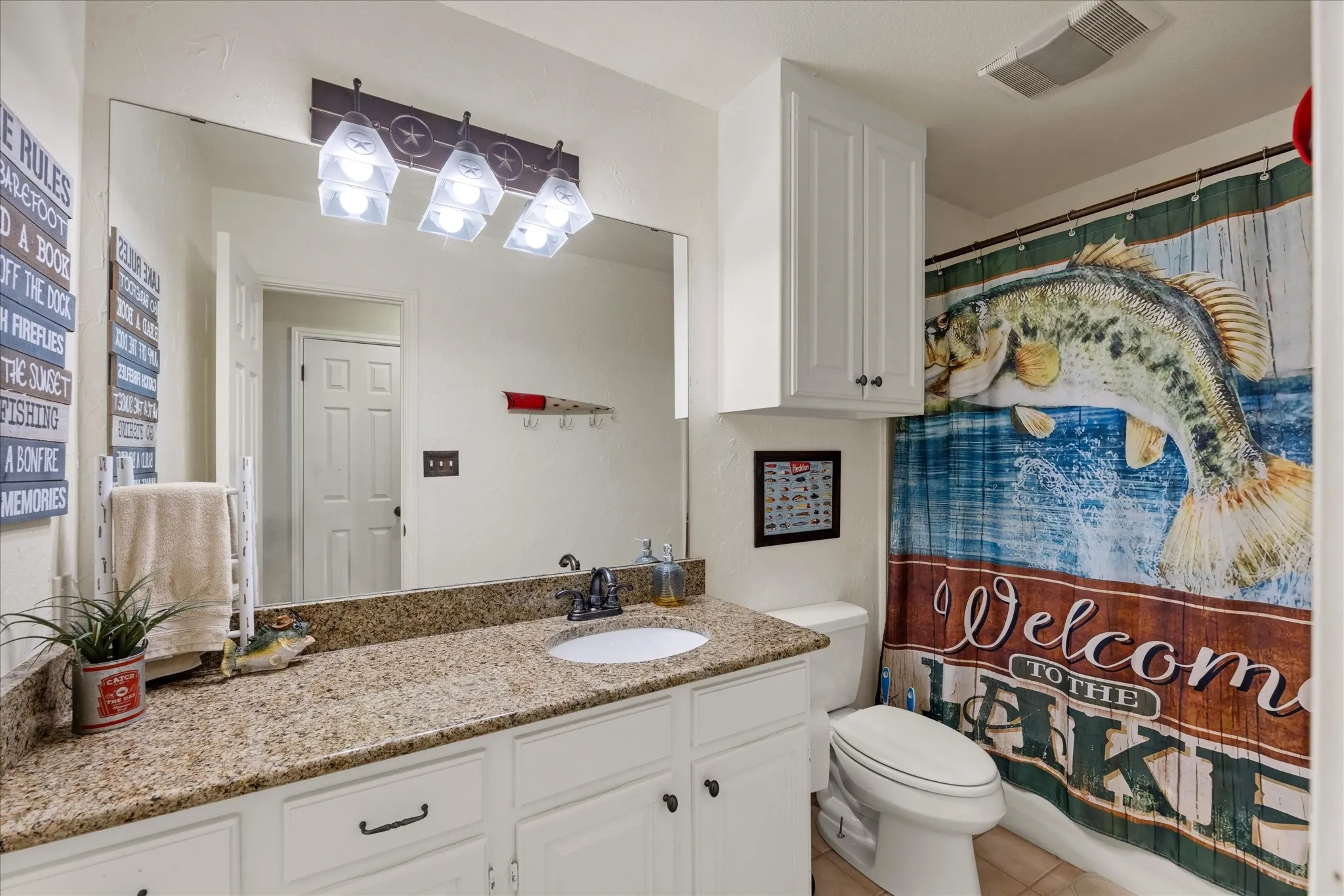 White vanity cabinetry with a single integrated sink, granite-style countertop, and a vanity mirror