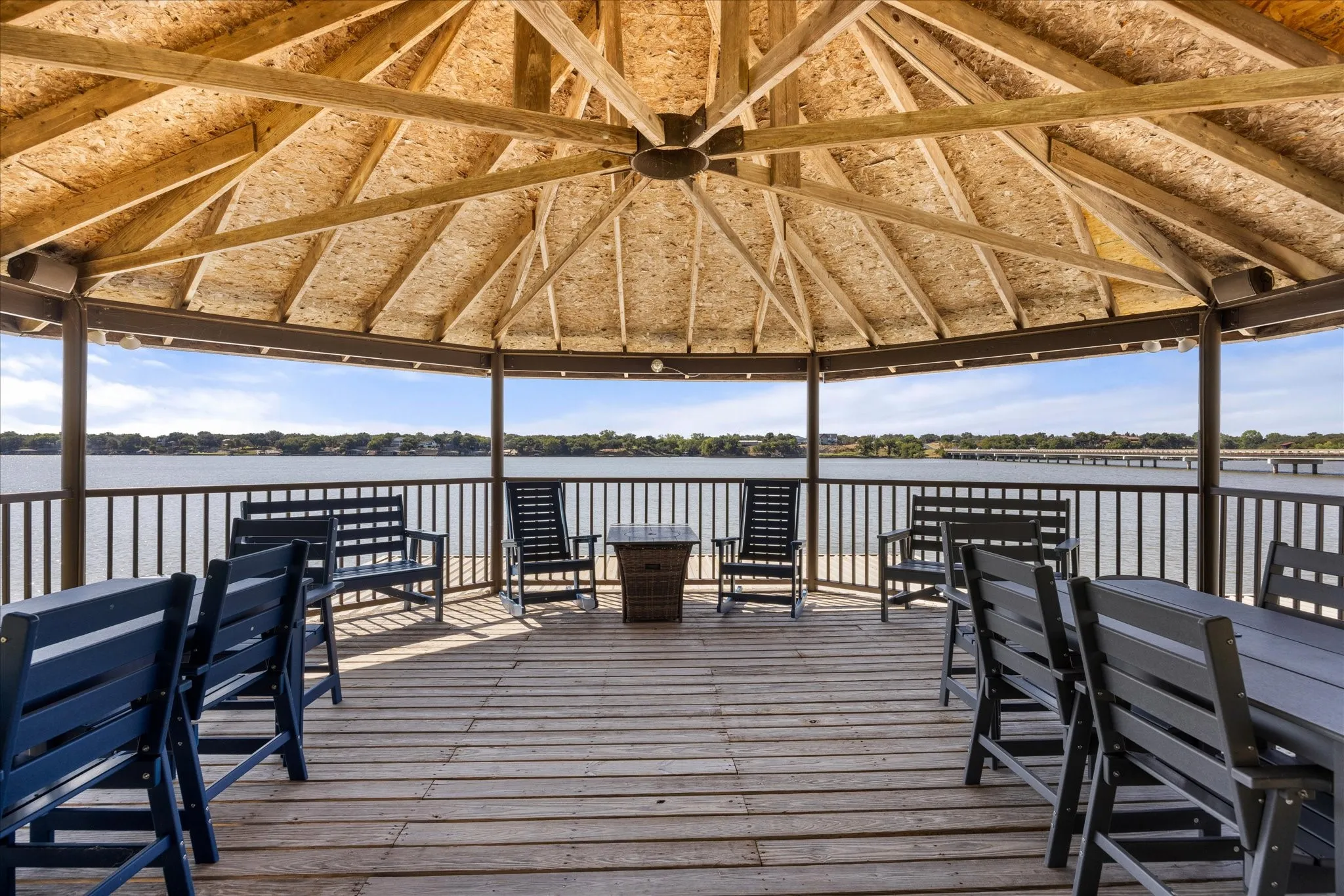 Octagonal gazebo with thatch-style roof and metal framing overlooking waterfront