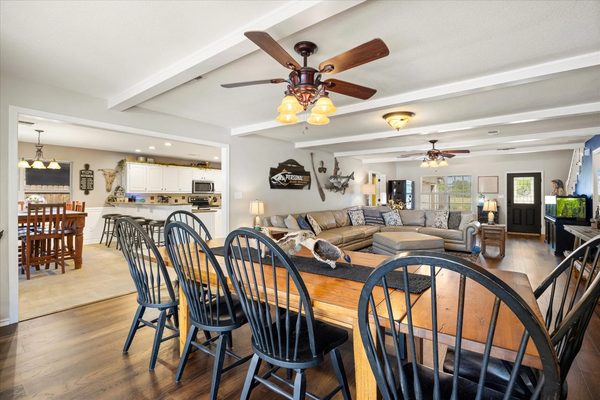 Open-concept living area featuring wood-finish flooring throughout, coffered ceiling with recessed lighting, and ceiling fan with integrated light fixture