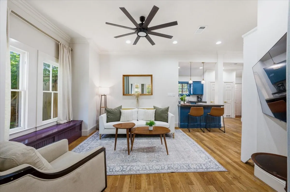 Wood-finish flooring throughout, bright white walls, crown molding, and a modern ceiling fan