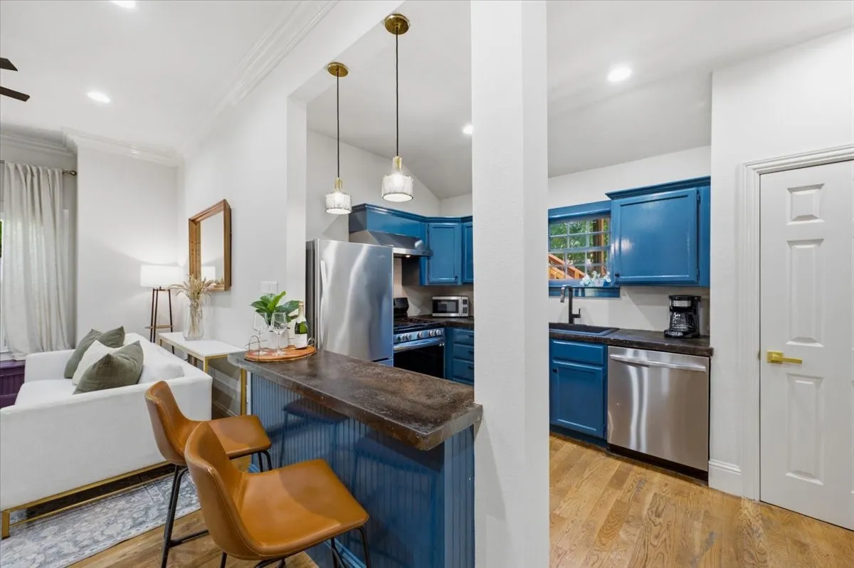 Open-concept living area with wood-finish flooring, recessed lighting, and crown molding
