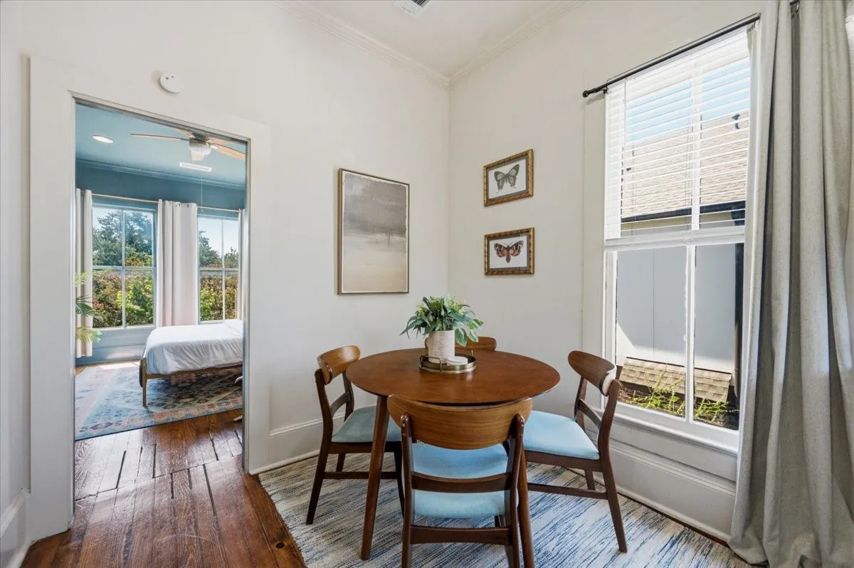 Hardwood flooring, painted white walls, and a window with blinds and drapery