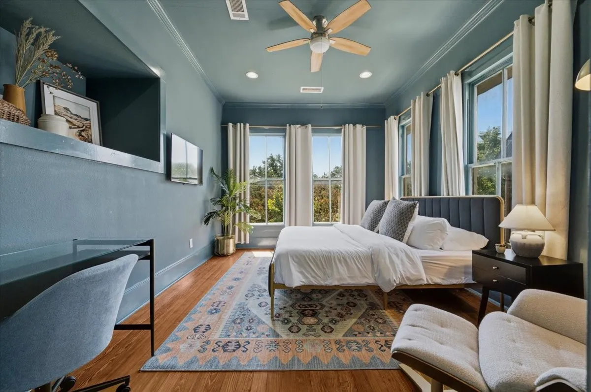 Wood-finish flooring, multiple windows providing natural light, built-in wall niche, and a ceiling fan with light fixture
