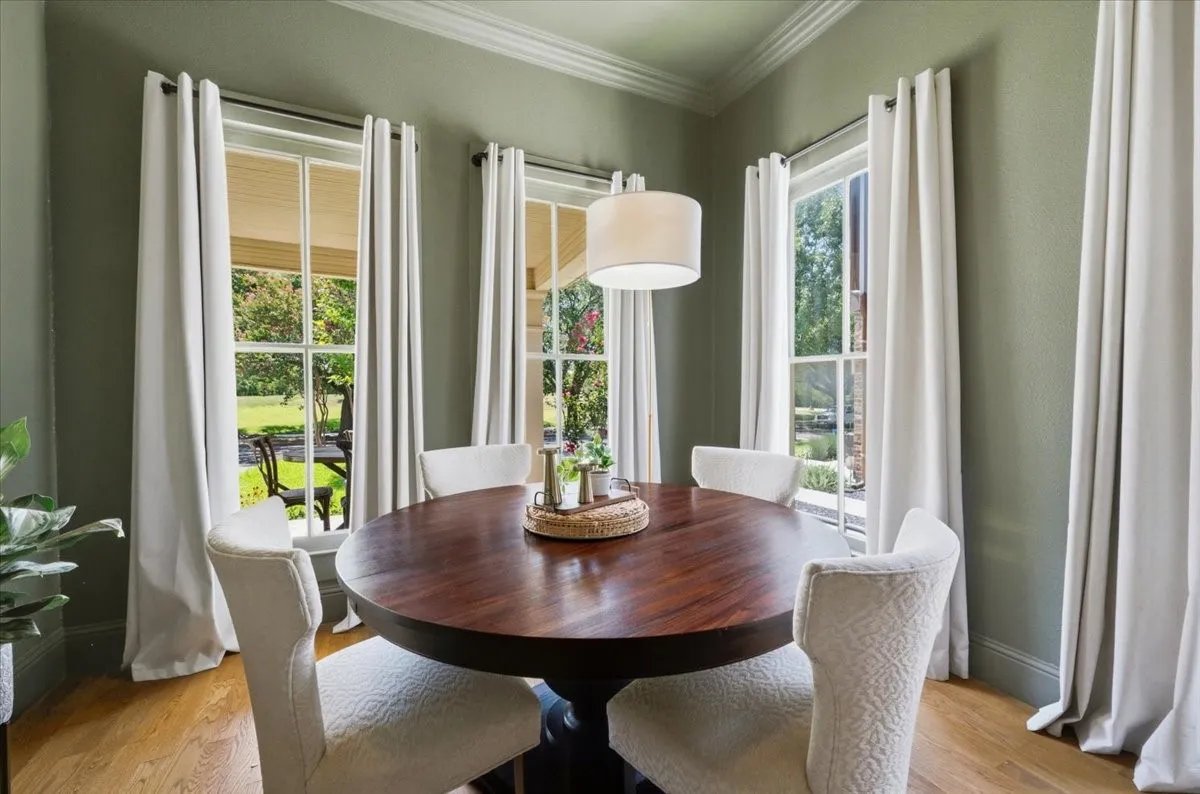 Wood-finish flooring, multiple pane windows, crown molding, and a drum pendant light fixture