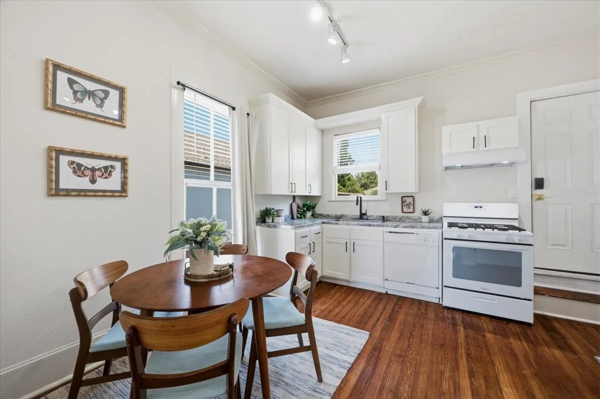 Kitchen featuring white cabinetry, light-toned countertops, a white gas range, and wood-finish flooring