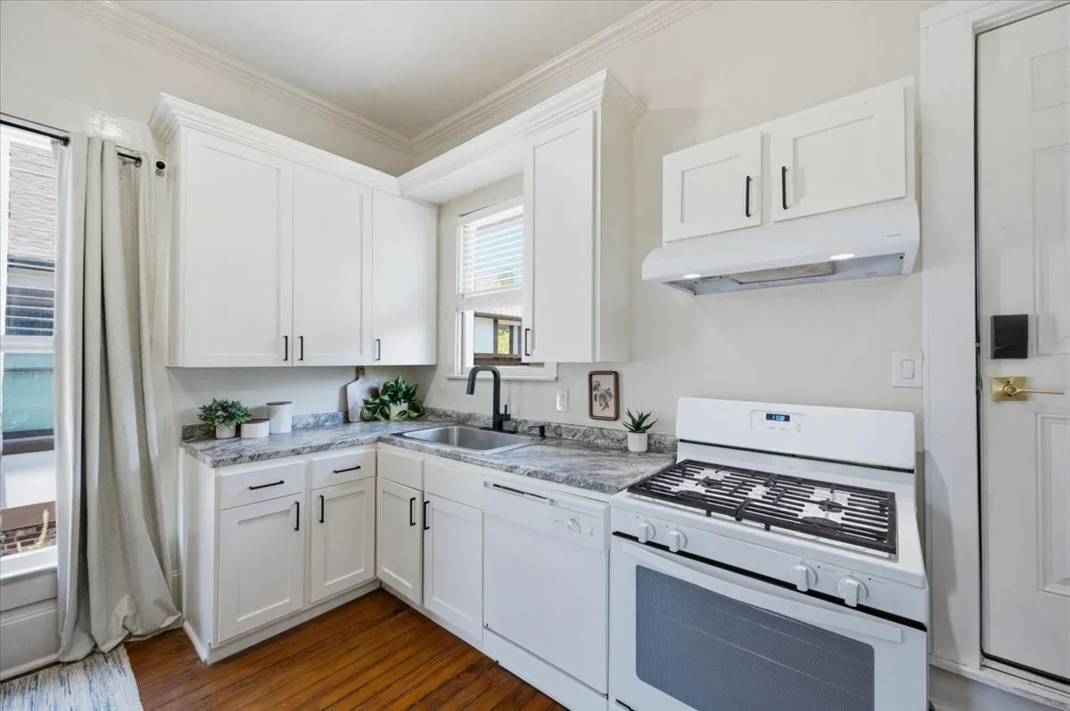 Kitchen featuring white cabinetry, grey countertops, stainless steel sink, and a gas range with an overhead hood