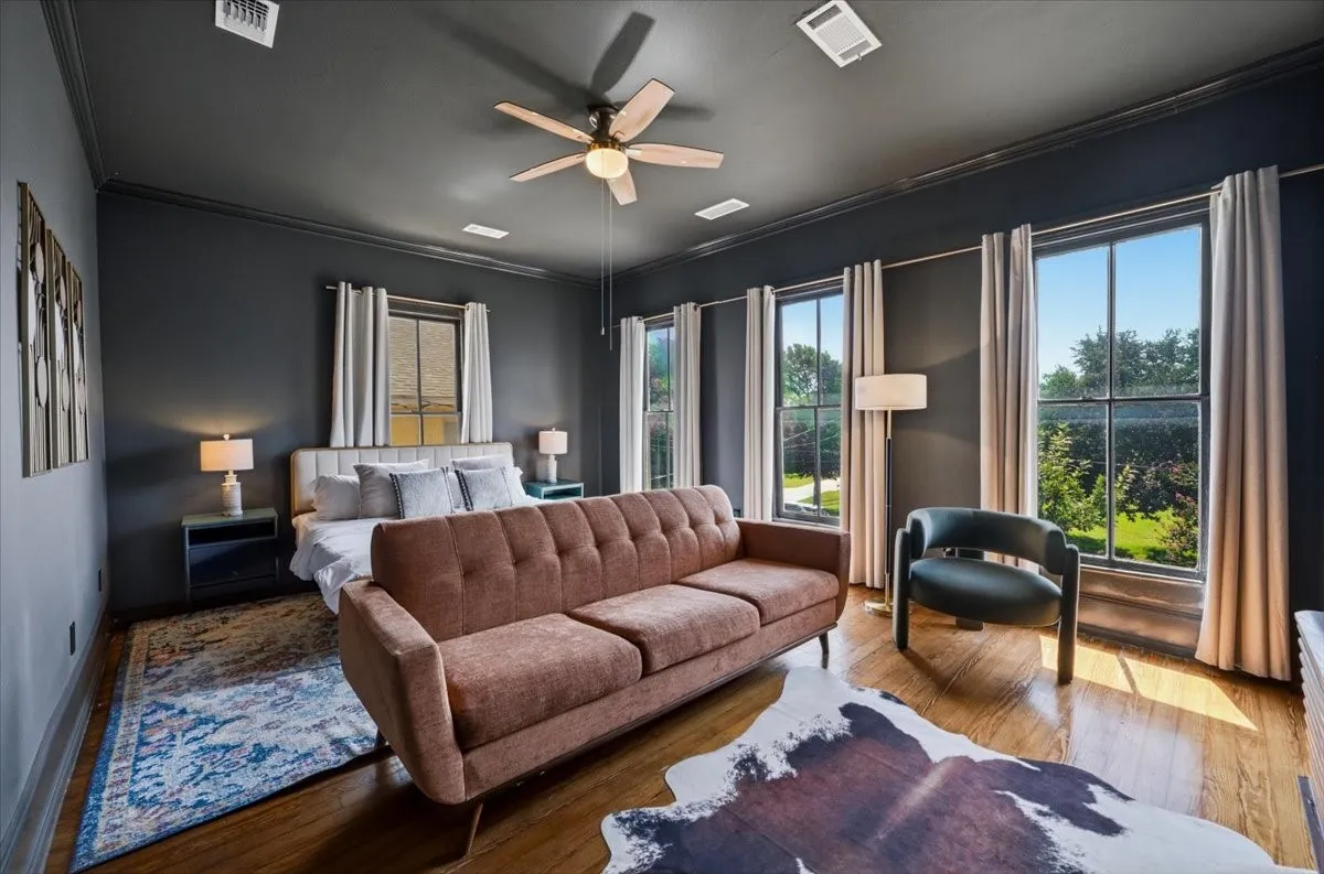 Hardwood flooring throughout, multiple large windows, ceiling fan, dark-toned walls, and recessed lighting