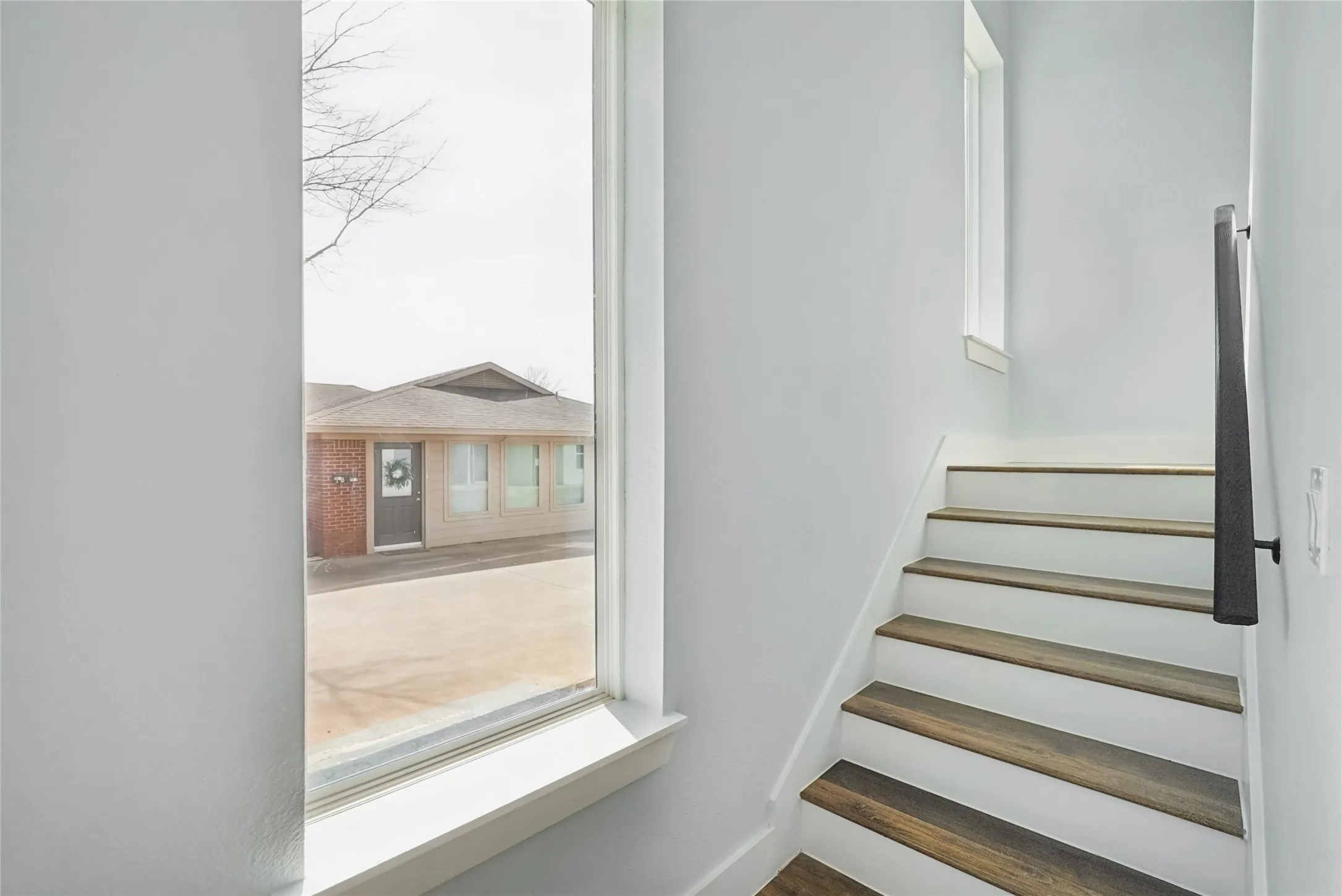 Staircase featuring wood-finish treads, white risers, and a contemporary dark handrail