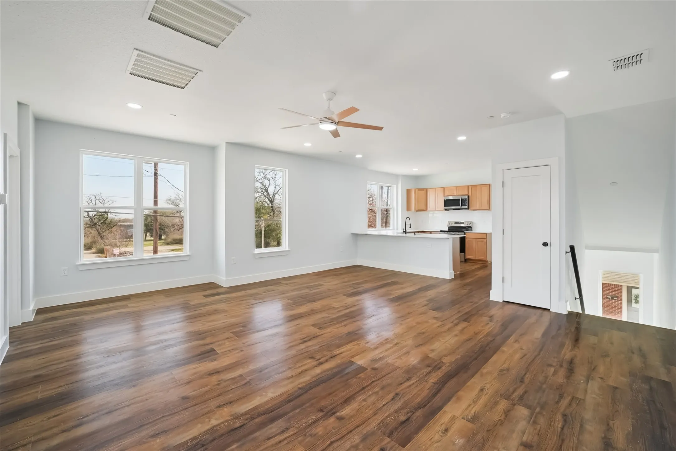 Open-concept living space with wood-finish flooring, recessed lighting, and a ceiling fan