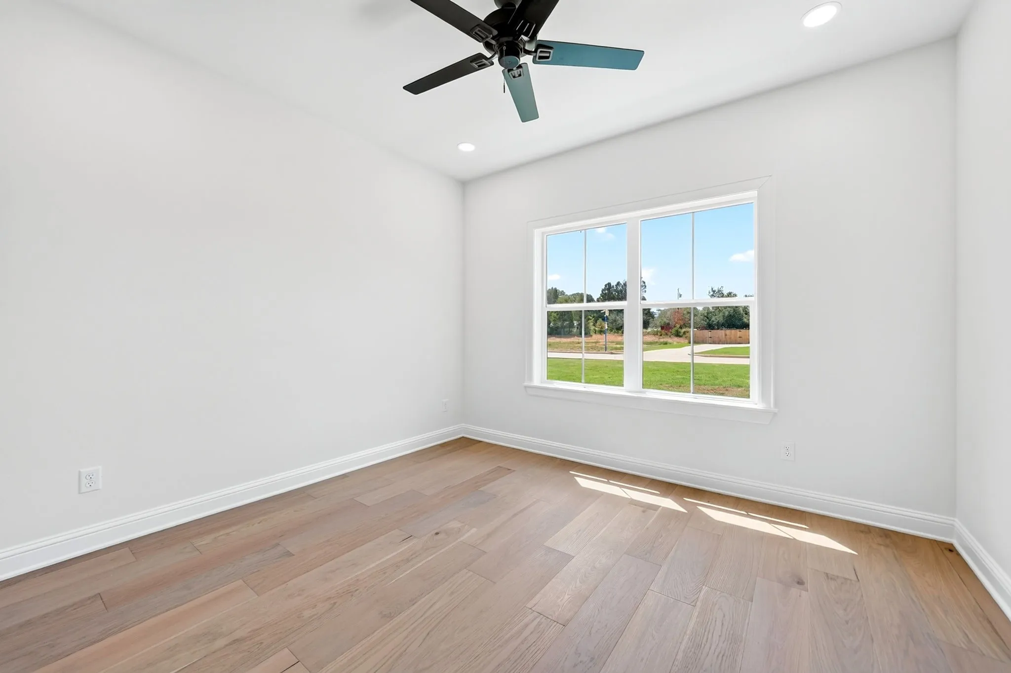 Neutral white wall finishes, wood-finish flooring, recessed lighting, and a ceiling fan with integrated lighting