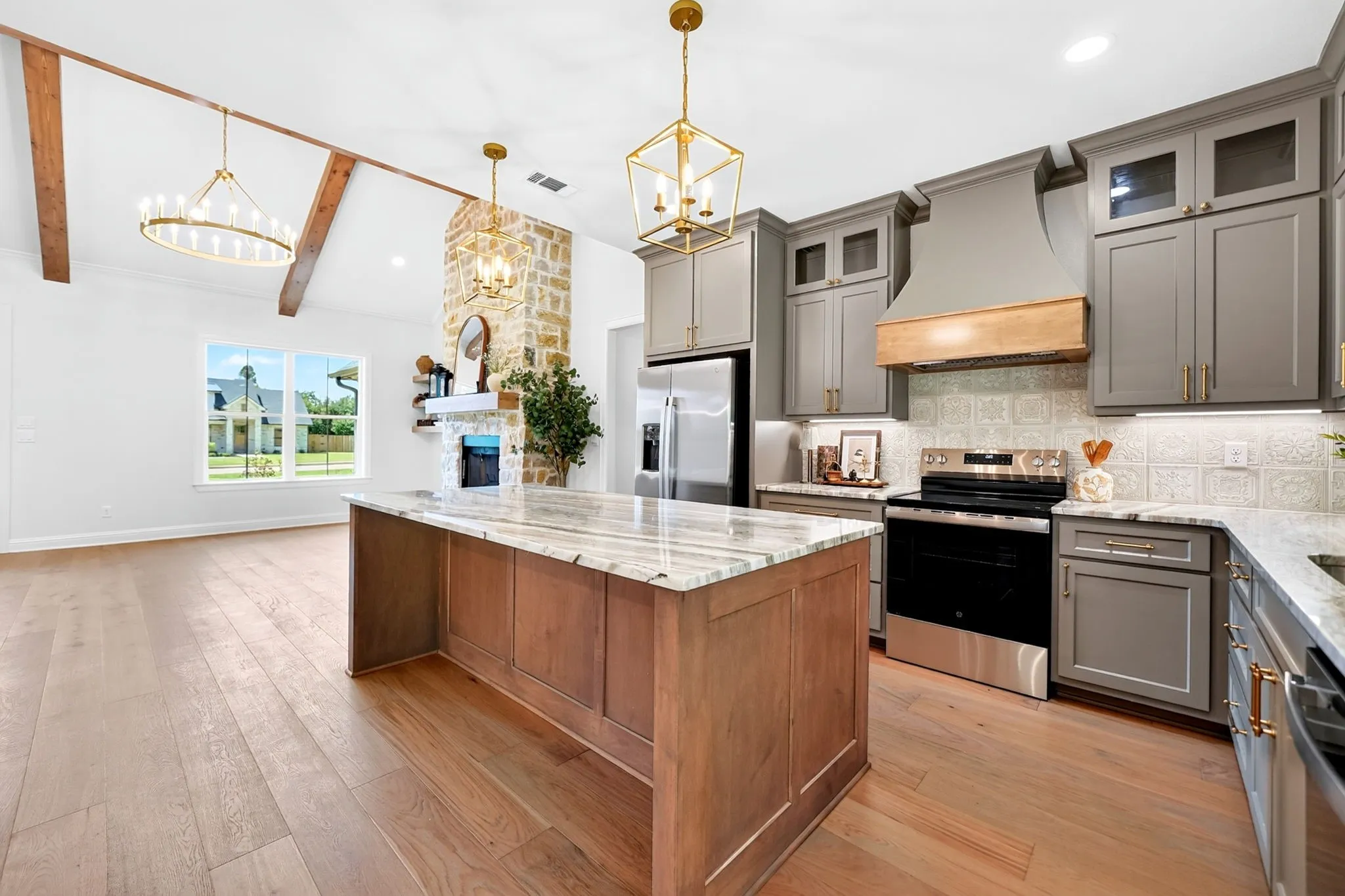 Spacious kitchen featuring an island with stone countertop, stainless steel appliances, and gray cabinetry