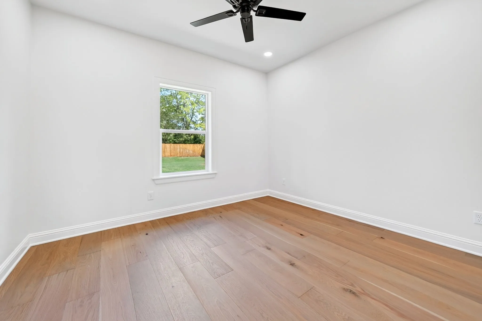 Vaulted ceiling with exposed wood beams, stone fireplace, wood-finish flooring, and recessed lighting